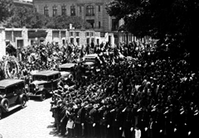 Multitud y miembros del Ejercito durante un cortejo funebre en una calle