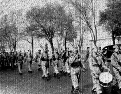 Banda de Guerra, escolta y contingente de soldados desfilando por una calle