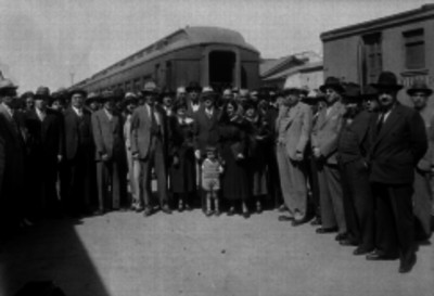 Hombres de traje y mujeres elegantes con niño a un lado del ferrocarril en la estación de San Lázaro, retrato