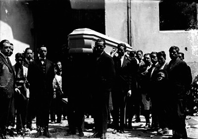 Hombres y militares durante cortejo fúnebre en un panteón