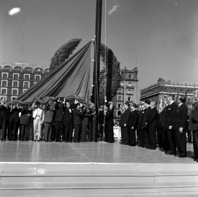Adolfo López Mateos con miembros de su comitiva izando la bandera monumental en el zócalo de la ciudad de México
