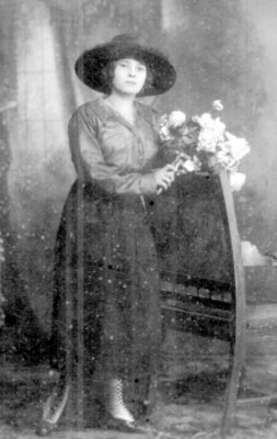 Mujer con ramo de flores de pie junto a una silla, retrato