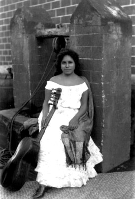 Mujer con guitarra sentada a la orilla de un pozo, retrato