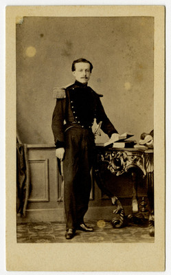 Hombre con uniforme militar parado junto a mesa