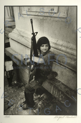 Mujer guerrilera sentada porta un arma, retrato