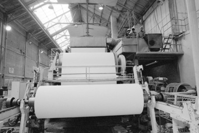 Obreros operan en máquina bobinadora de papel, fábrica San Rafael