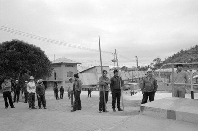 Trabajadores de pie con garrochas en patio de fábrica
