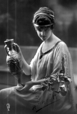 Mujer sentada de perfil tres cuartos, sostiene entre sus manos un jarro, tarjeta postal