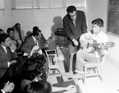 Maestro y alumnos durante clase de música en un salón