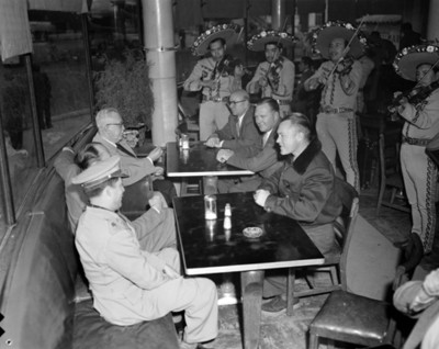 Hombres en comedor de un restaurante escuchen a mariachi