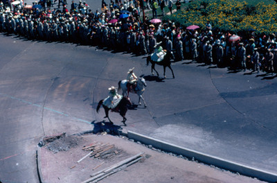 Mujeres vestidas con trajes regionales desfilan a caballo por calles y avenidas