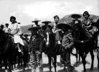 Mujeres montan a caballo junto a unos charros