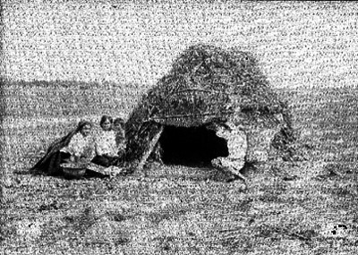 Familia indígena afuera de un jacal en un llano