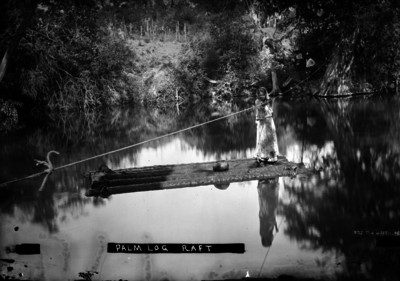 Niña navega por un río en balsa hecha con troncos