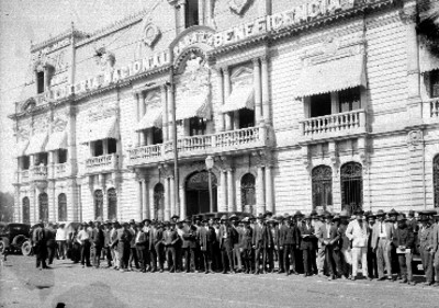 Hombres frente al edificio de la Lotería Nacional, retrato de grupo