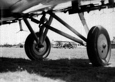 Pilotos empujando un avión y llantas de otro avión en primer plano