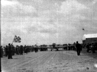 Hombre dando banderazo a un avión, en los campos de Balbuena