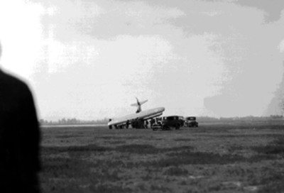 Militares y otras gentes junto a un avión accidentado en campo aéreo