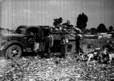 Pepenadores junto a un camión recolector de basura, en un vertedero