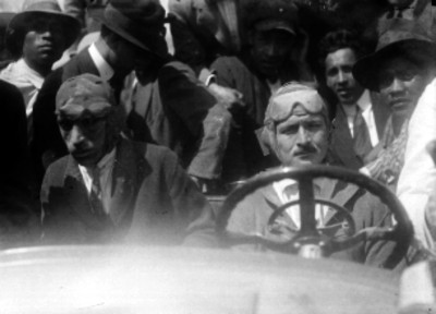 Pilotos en su auto de carreras acompañados por varios hombres, retrato de grupooo