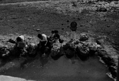 Mujeres lavando ropa en un estanque acompañadas de niños