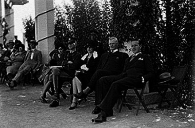 Público de militares, hombres y mujeres elegantes en el teatro de art-deco al aire libre durante el festival de la conquista