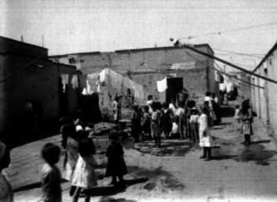 Niños acarreando agua en la pileta de una vecindad de condición humílde