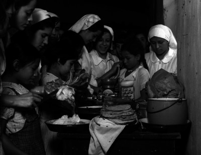 Monjas enseñando a unas niñas a cocinar, probablemente en la cocina de un convento