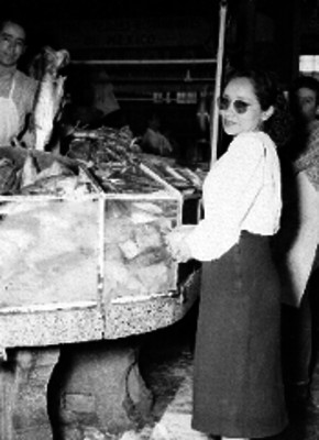 Mujer comprando pescado y hombre mostrando un pescado grande