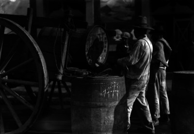 Hombres estiban barriles de pulque a una carreta