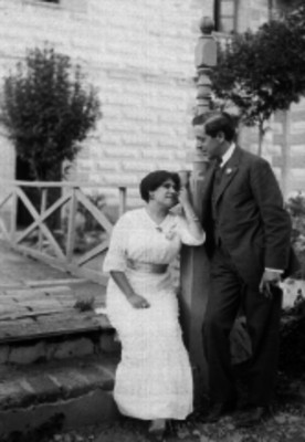 Pareja tomada de la mano conversando en el jardín de una casa de campo
