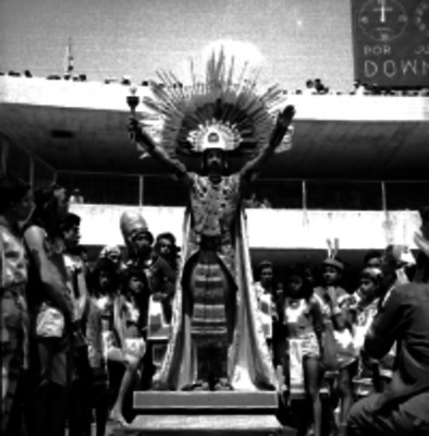 Hombre con un penacho y taparrabos levantando los brazos en una representación azteca
