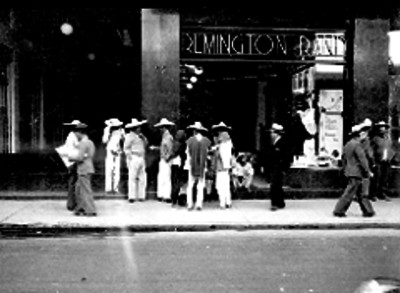 Mariachi esperando trabajo en una calle, frente a un almacen