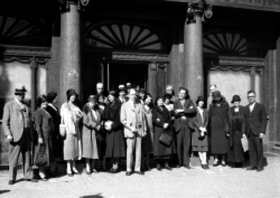 Grupo de turistas extranjeros, ya maduros de edad, al frente de la entrada del hotel Regis, retrato