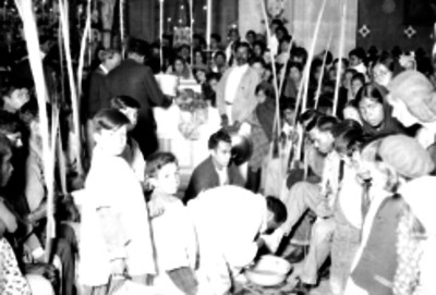 Sacerdote escenificando el lavado de pies a un anciano durante los festejos del jueves santo