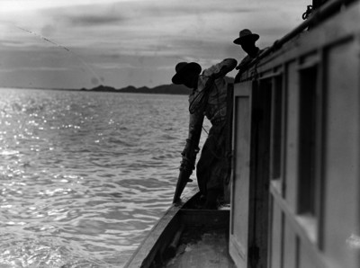 Pescadores sibiendo un chinchorro a una embarcación