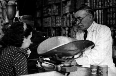 Comerciante atendiendo a mujer, en tienda de abarrotes