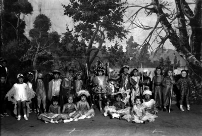 Niños y niñas vestidos con diferentes trajes folclóricos en un parque, retrato