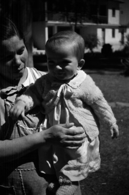 Niño con muñeco dentro de una carreola en un jardín, retrato