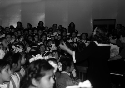 Coro de niños dirigido por una mujer durante un concierto en la feria del ritmo