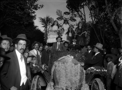 Personas con trajes folclóricos en un carro alegorico durante festividades de la colonia española