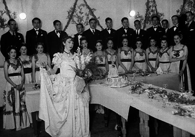 Quinceañera acompañada de sus damas y chambelanes junto a un pastel, retrato de grupo