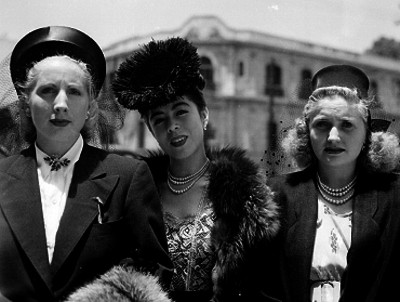 Mujeres vestidas elegante con sombrero de velo en una calle, retrato de grupo