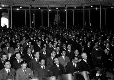 Público varonil asistente a un evento en un salón de actos