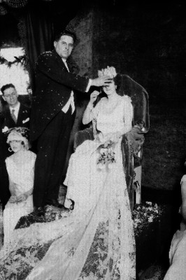 Hombre coronando a una reina durante un festejo en un salón