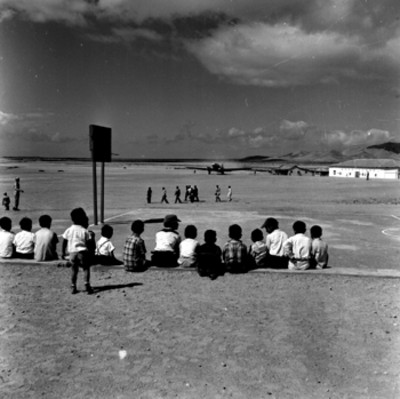 Niños observando la llegada de Adolfo López Mateos y funcionarios en un aeropuerto