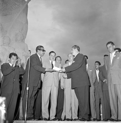 Adolfo López Mateos recibiendo un documento de manos de un hombre en la escuela Héroes de Chapultepec