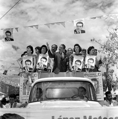 Adolfo López Mateos y edecanes en un camión, haciendo un recorrido en su campaña electoral