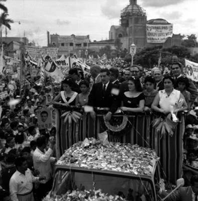 Adolfo López Mateos con mujeres a bordo de un camión saludando a partidarios