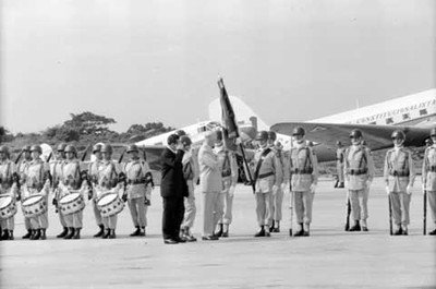 Adolfo López Mateos realizando el saludo militar cuando Lyndon B. Johnson entrega la bandera a un soldado